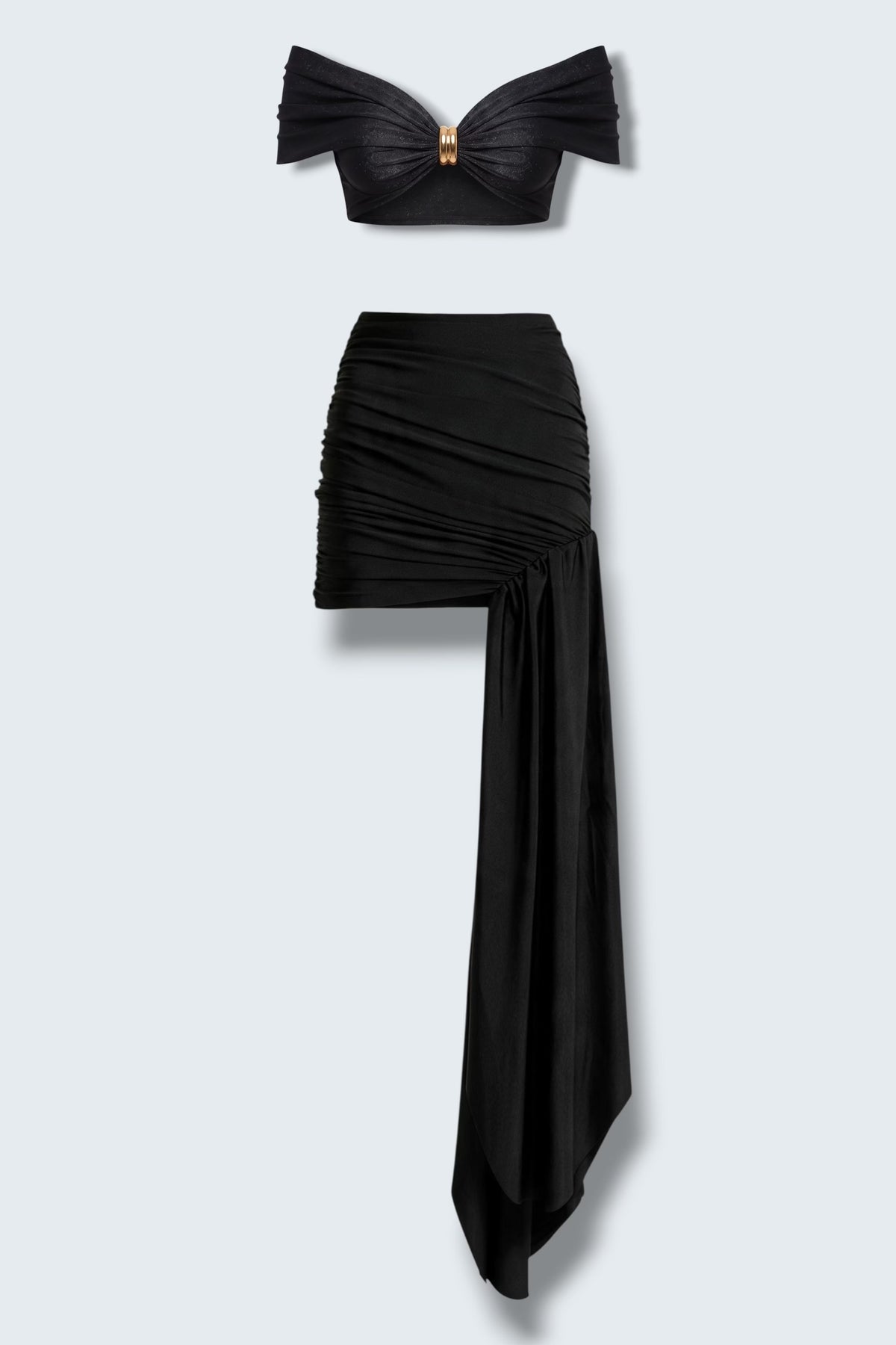 The Saint 54 black two-piece set with a draped off-shoulder crop top, gold hardware, and an asymmetrical mini skirt.