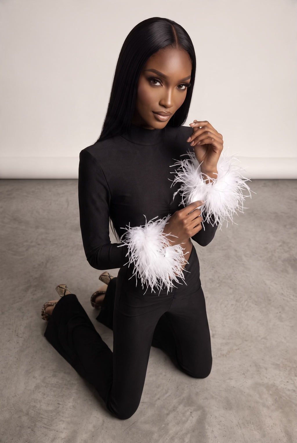 The Saint 54 black fitted top with detachable white ostrich feather cuffs and matching high-waisted flared trousers.