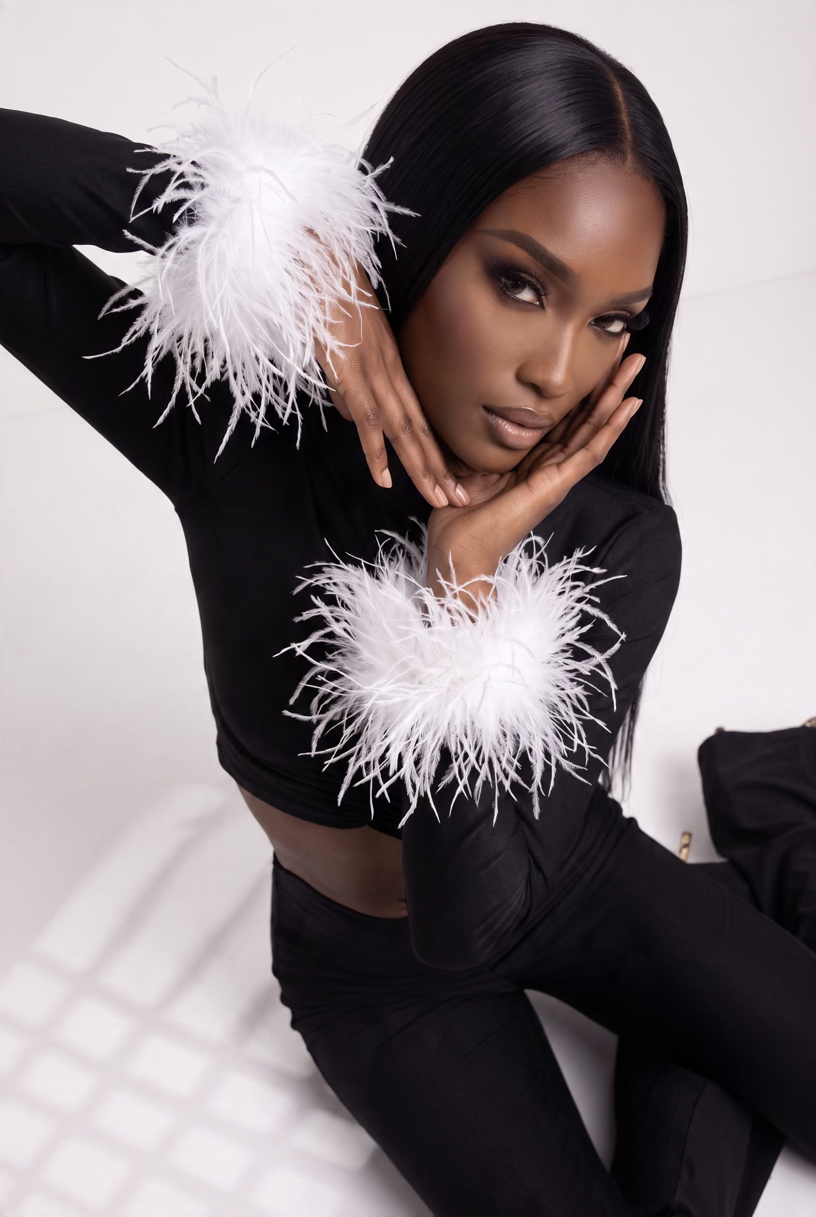 The Saint 54 black fitted long-sleeve top with detachable white ostrich feather cuffs and polo-style neckline.