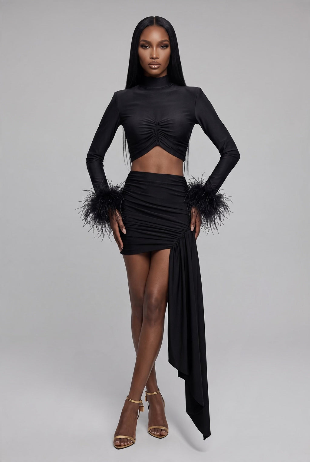 Model wearing The Saint 54 black long-sleeve crop top with ostrich feather cuffs and matching ruched mini skirt