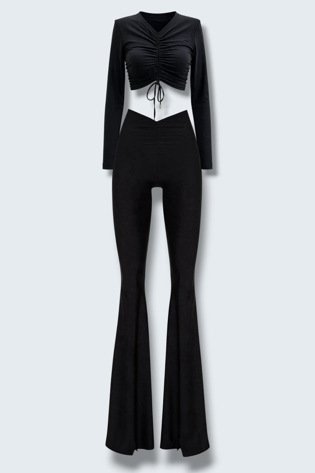 The Saint 54 black two-piece set featuring a long-sleeve ruched crop top and high-waisted flared trousers with slits.
