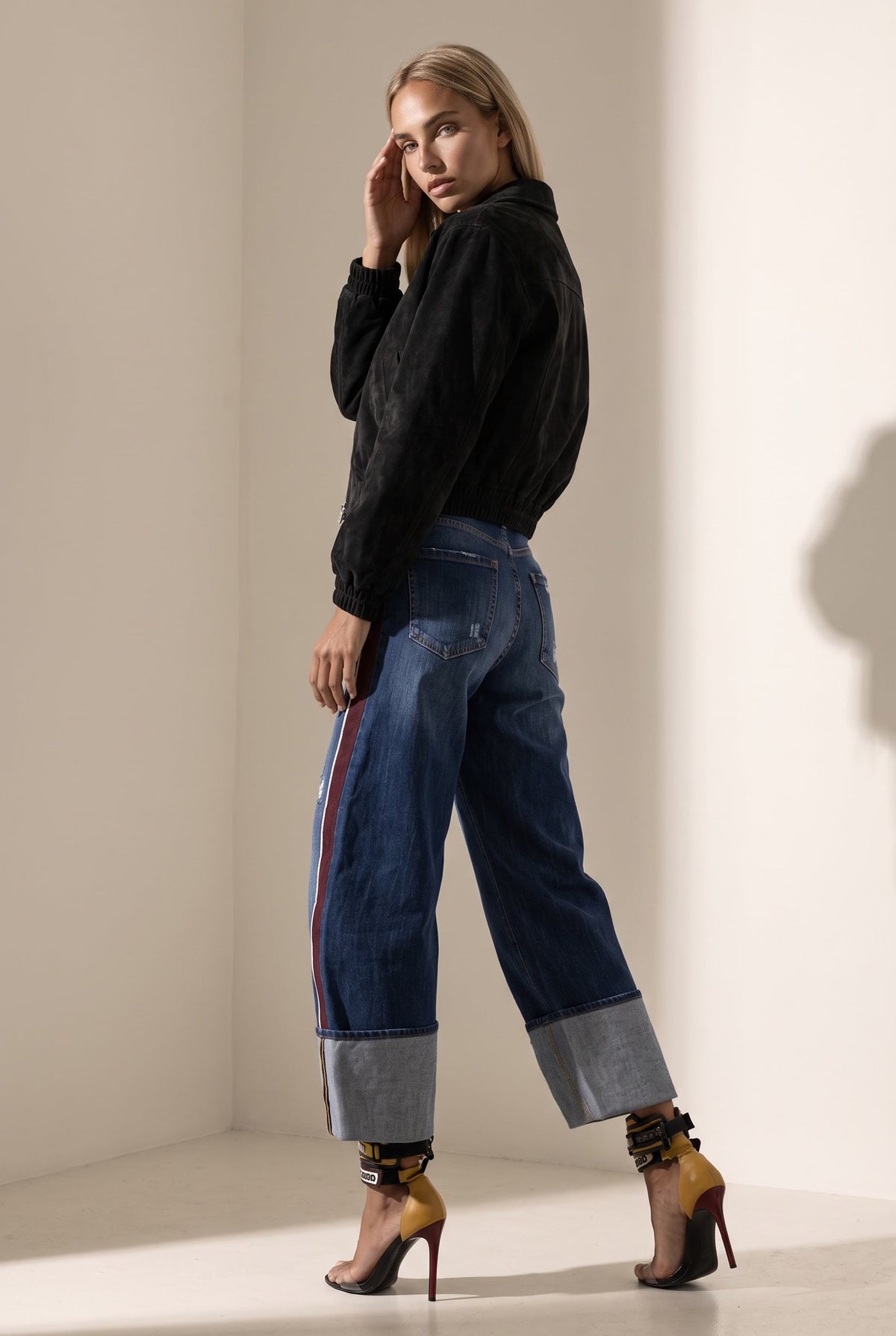 The Saint 54 black suede bomber jacket with an oversize fit, shoulder pads, and satin lining worn by a model.