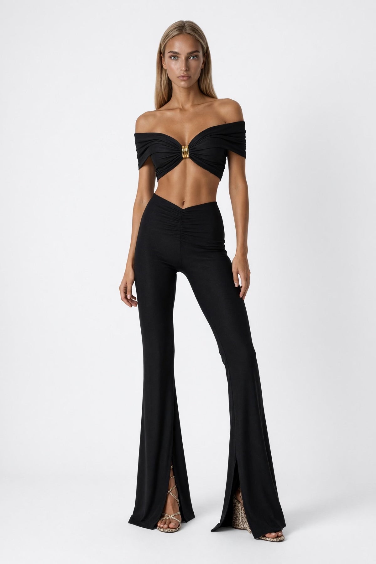 The Saint 54 black two-piece set featuring an off-the-shoulder crop top with gold hardware and flared slit trousers.